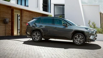 RAV4 Plugin Hybrid wird vor der Garage eines modernen Wohnhauses per Plugin aufgeladen