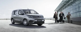 Toyota Proace City Verso auf einem Flughafengelände - Businesspeople mit Koffern laufen vom Auto zum Terminal