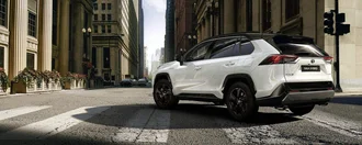 Weißer Toyota Rav4 biegt in Häuserflucht einer modernen Stadt ein