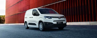 Weißer Toyota Proace City vor einem roten Gebäude