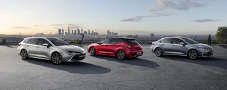 Alle Toyota COROLLA Modelle auf einem Platz mit Blick auf modernes Stadt- und Industriegebiet: Toyota Corolla, Toyota Corolla TS und Corolla Limousine