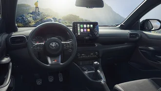 Cockpit des Toyota GR Yaris - im Hintergrund eine Person auf einem Felsvorsprung im Gebirge