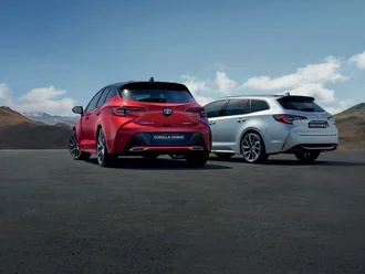Zwei Toyota Corolla von der Asphaltnabe aus fotografiert vor bergigem Hintergrund