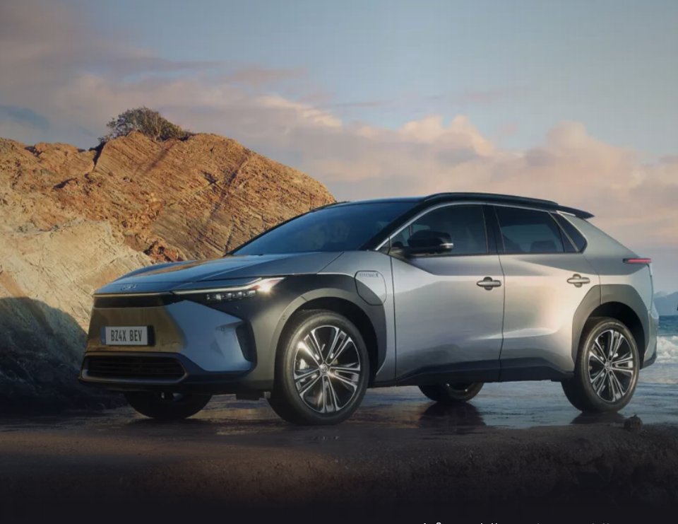 Seitendarstellung des Toyota bZ4X an einem Strand vor einem Felsen. Im Hintergrund sind Wolken über einem Meer zu sehen.